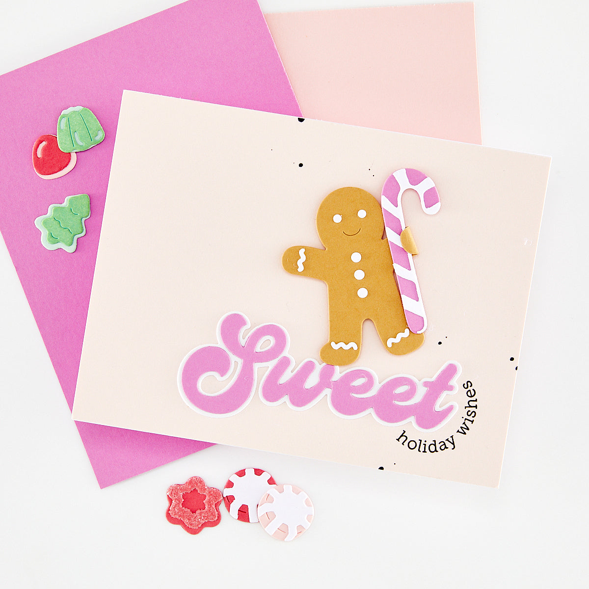 Handmade greeting card in pale mauve with other shades of purple cards in the background. Card features the words 'Sweet holiday wishes' with a gingerbread person holding a candy cane