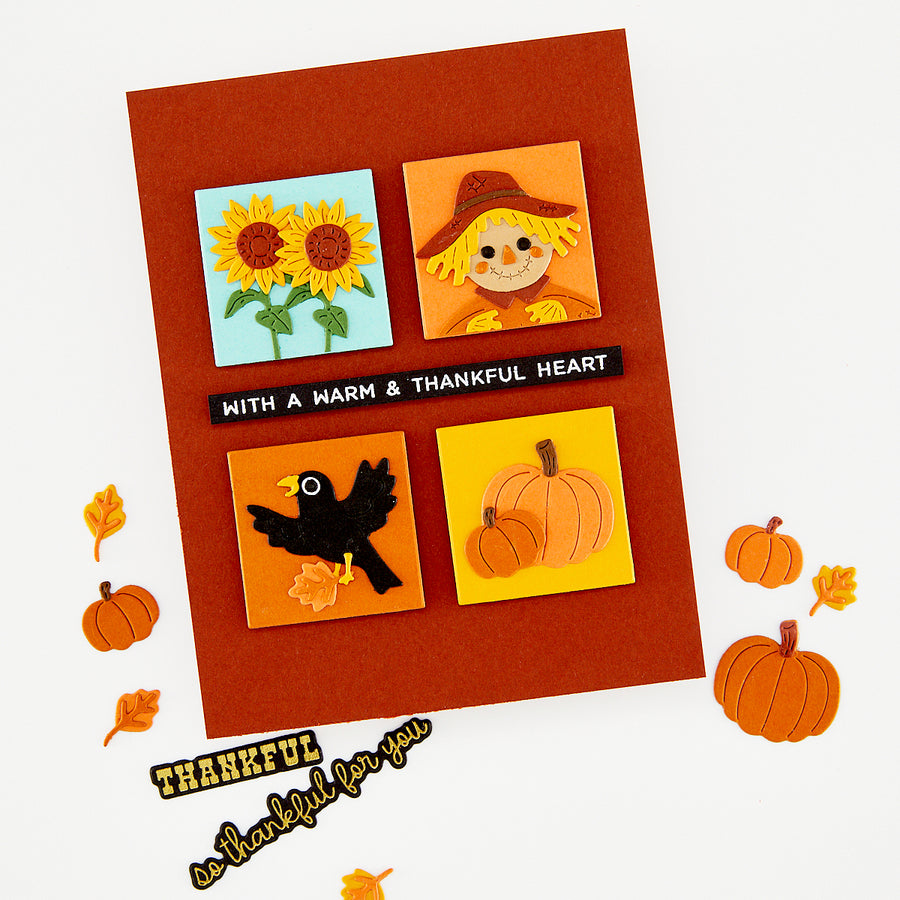 A handmade autumn-themed greeting card with a rust-orange background and four colorful square illustrations: sunflowers, a scarecrow, a black bird, and pumpkins. A black banner across the center reads 'WITH A WARM & THANKFUL HEART. Using Hero Arts Beep Beep Leaf Peeper Die Set