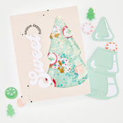 A flat-lay of a handmade greeting card with a die-cut white 'Sweet' script and a window showing a mint green Christmas tree filled with colorful confetti and candy decorations. Surrounding the card are matching mint green die-cut embellishments, including a Christmas tree, a candy cane, and a gingerbread man, on a clean white background.