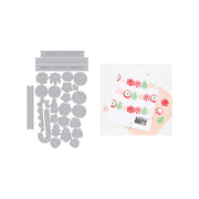A holiday-themed crafting set shown on a white background, featuring a gray metal die-cut sheet with Christmas motifs and text, alongside a printed card or sticker sheet with matching holiday illustrations and a peach envelope.