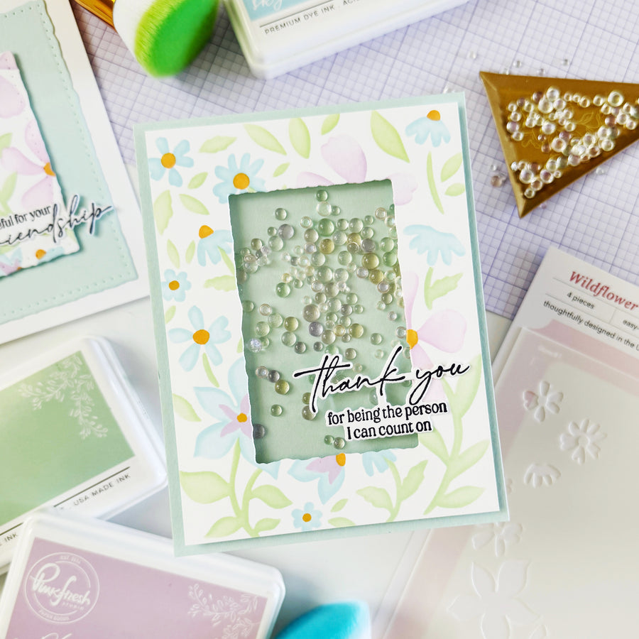 Handmade card with floral design and 'thank you' message on a crafting table.