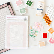 Stamping supplies including stamps, ink pads, and a clear block on a white surface.
