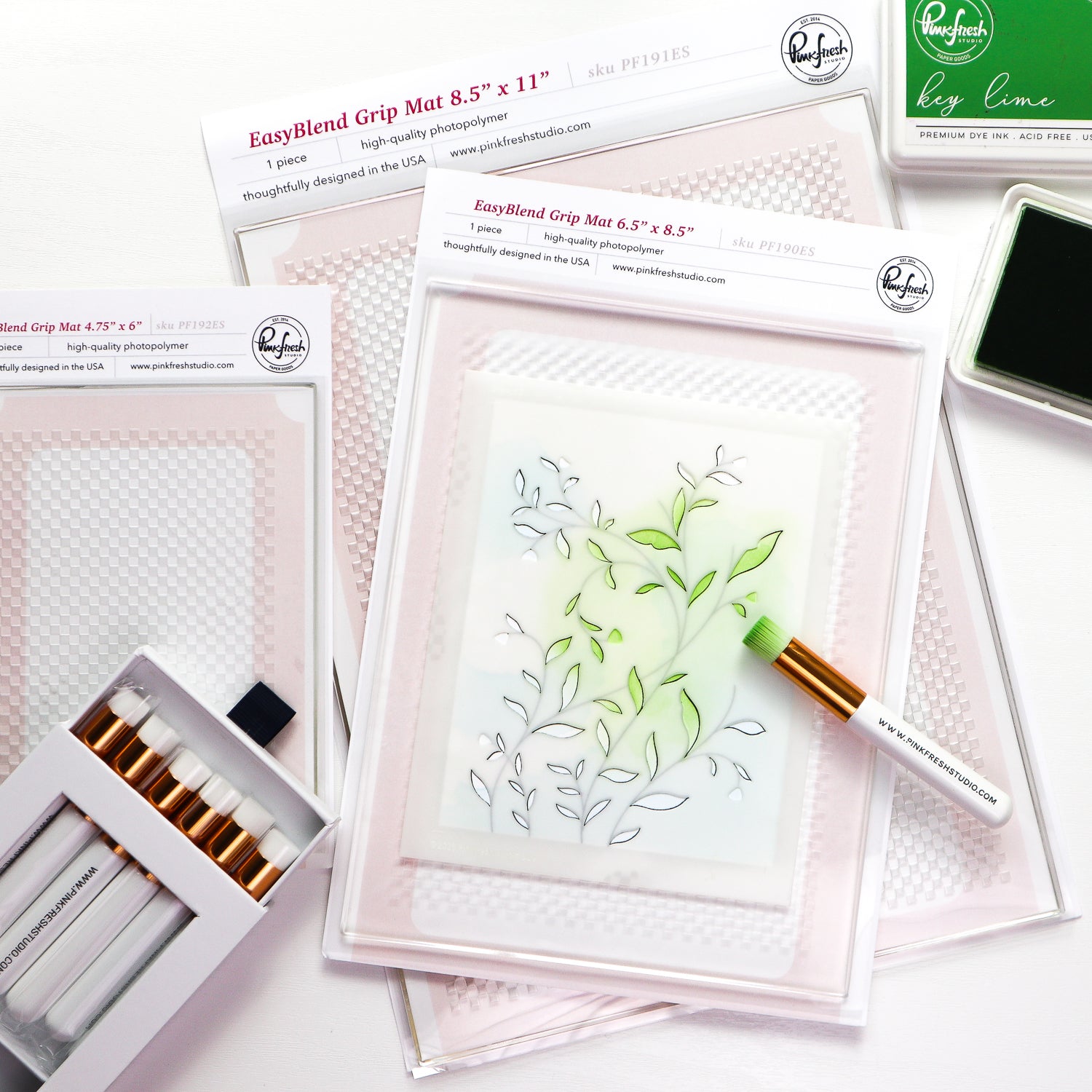 A flat-lay product shot of a clear stamping kit with multiple components including a clear stamp sheet with green leaf designs, a white EasyBlend Grip Mat, a box of white markers, and an ink pad, all branded with 'pickledheadbuns' on a white background.