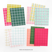 Six sheets of patterned paper arranged in two overlapping stacks on a white background. The papers feature plaid and grid patterns in various colors including green, pink, yellow, orange, and blue on white bases.
