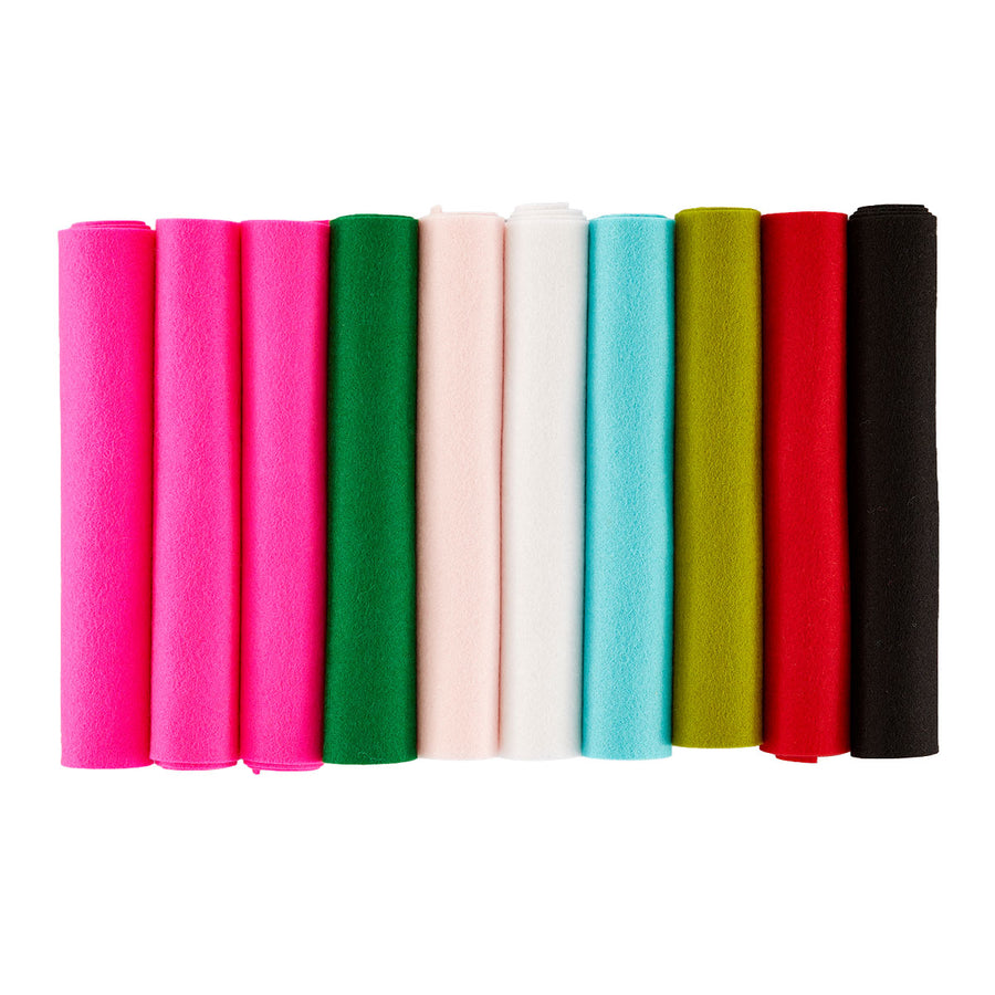 A set of ten rolled felt strips in assorted colors, including pink, green, pale pink, white, light blue, olive green, red, and black, arranged vertically in a row on a plain white background. Spellbinders Merino Wool Felt Sheets - Festive Collection