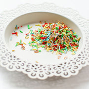 Multicolor miniature clay confetti with tiny printed illustrations, scattered on a white ceramic plate with a scalloped lace edge. Pretty Pink Posh Fall Fling Clay Confetti
