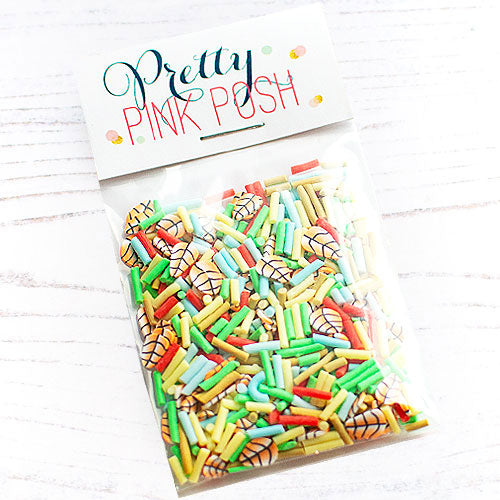 A clear plastic bag filled with colorful sprinkles and autumn leavess, sealed with a white paper header card that reads 'Pretty Pink Posh' in decorative lettering, photographed on a white wood surface. Pretty Pink Posh Fall Fling Clay Confetti