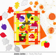 An autumn-themed handmade card featuring a plaid orange and yellow border with felt fall elements including acorns, leaves, a sunflower, mushrooms, and a pumpkin. The card is displayed on orange paper with scattered felt cutouts and decorative pearls around it.