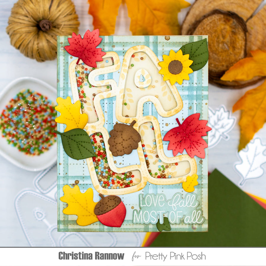 A handmade autumn-themed card featuring the word 'fall' in layered beige letters filled with multicolored confetti, decorated with red and yellow leaves, acorns, sunflowers, and green leaves on a light blue plaid background. The card is displayed on a white surface with craft supplies, and the text 'Christina Rannow for Pretty Pink Posh' appears at the bottom.