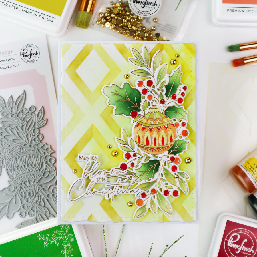 A handmade Christmas greeting card featuring a yellow and green chevron background, a die-cut ornament, holly leaves, red berries, and the phrase 'You are my Christmas' in white script. The card is styled on a white surface with crafting tools and brands like Perfect and Winchell visible around it.