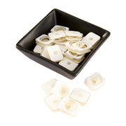 A black square bowl filled with small off-white plastic square caps, with several loose matching caps placed in front on a white background. Spellbinders Giggle Springs