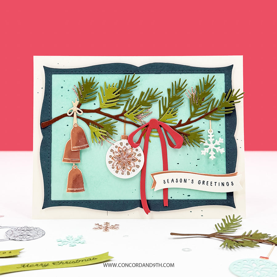 A handmade layered Christmas greeting card featuring pine branches, hanging copper bells, a red ribbon bow, a white snowflake ornament, and a banner reading 'SEASON'S GREETINGS' on a white background with a coral-red upper backdrop.