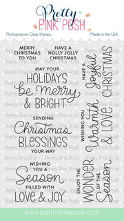 A sheet of Pretty Pink Posh photopolymer clear stamps featuring various Christmas-themed phrases in black and blue script and serif fonts, shown on a white background with a light gray patterned backdrop. Pretty Pink Posh Inside Sentiments: Christmas Stamp Set