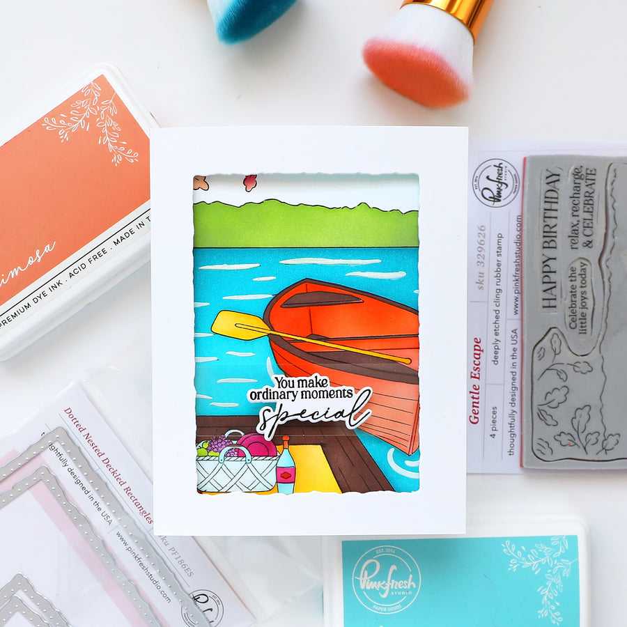 Colorful card with a paddle and scenic design on a white surface with craft supplies.