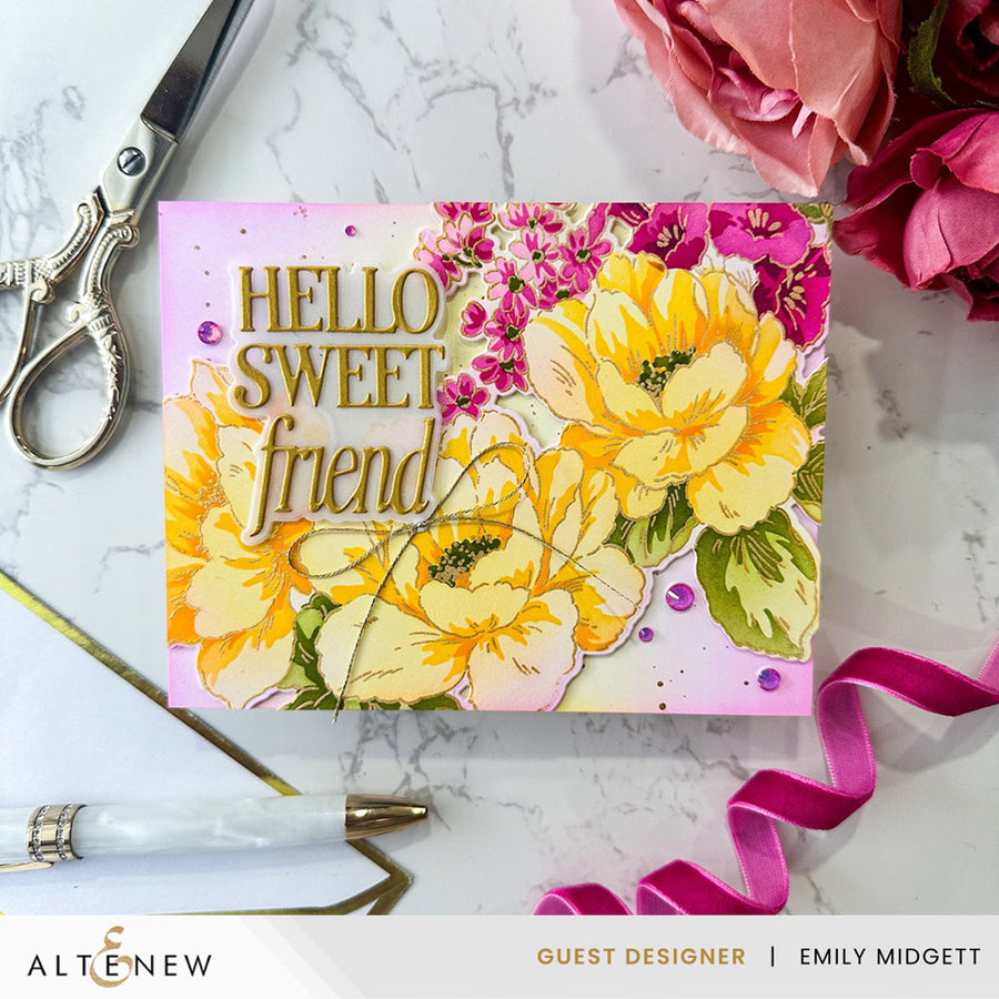 A handmade greeting card with a floral design and the text 'HELLO SWEET friend' in gold foil, styled on a white marble background with scissors, a pen, ribbon, and pink flowers.