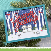 A handmade layered greeting card with a turquoise border, featuring a winter forest scene with white birch trees, red birds, a blue polka-dot background, a white snow-covered ground, and red script text reading 'Seasons Greetings.' Two small die-cut animal figures sit in the snow, surrounded by greenery and snowflake embellishments.