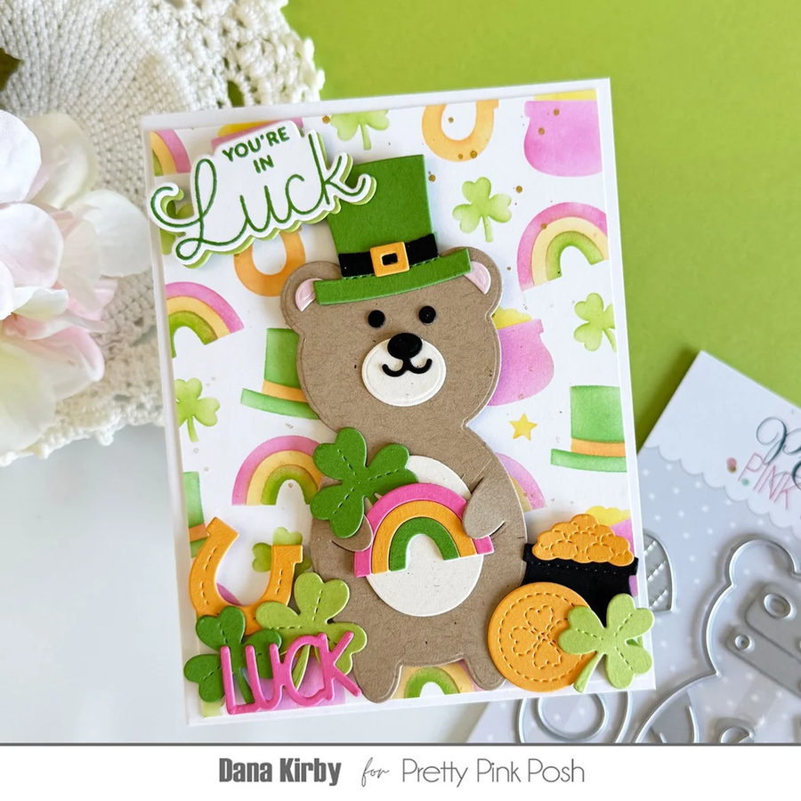 A handmade St. Patrick's Day card featuring a brown bear wearing a green hat and holding a shamrock, surrounded by rainbows, clovers, and gold coins, with a 'YOU'RE IN Luck' banner.