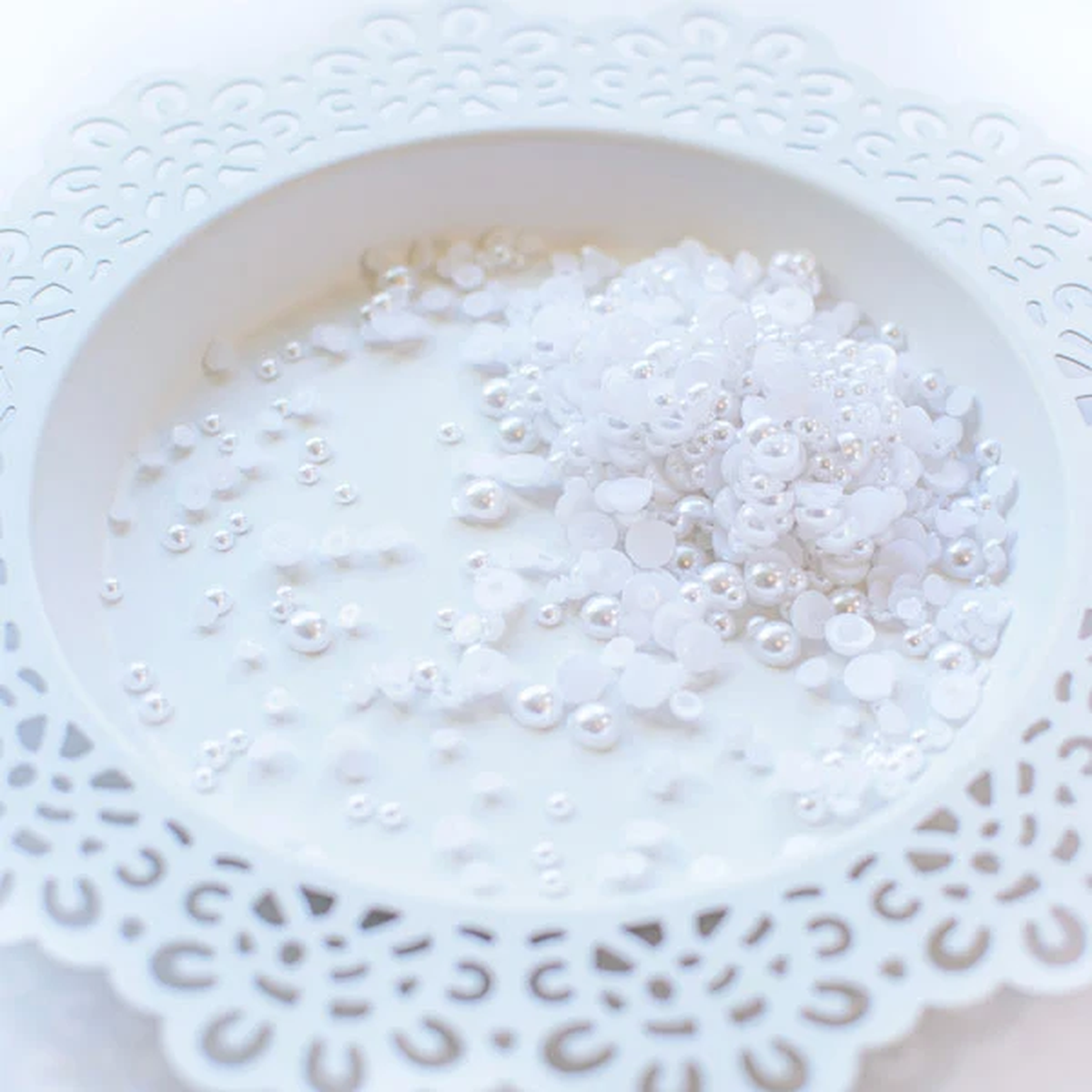 White craft pearls piled in a white ceramic dish with a scalloped cutout edge. Pretty Pink Posh Marshmallow Pearls