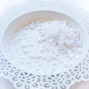 White craft pearls piled in a white ceramic dish with a scalloped cutout edge. Pretty Pink Posh Marshmallow Pearls