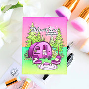 Colorful card with a purple camper and trees, surrounded by stationery items on a white background.