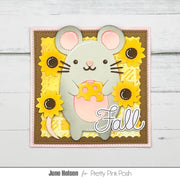 A handmade autumn-themed card featuring a gray mouse holding a yellow cheese wedge, surrounded by yellow sunflowers and the word 'Fall' in white script. The card is displayed on a light gray wood background with a white border at the bottom containing the text 'June Helsen for Pretty Pink Posh'.