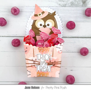 A Halloween-themed treat box filled with pink and red wrapped candies, featuring a cute owl wearing a witch hat on the front. The box has 'TRICK or TREAT' written on it and is styled on a white wood background with scattered pink candies.