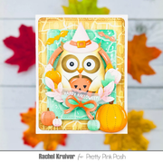 A handmade Halloween greeting card featuring a cute owl dressed as a witch, surrounded by pumpkins, leaves, and a 'Happy Halloween' banner. The card is displayed against a white wood background with colorful autumn leaves scattered around.