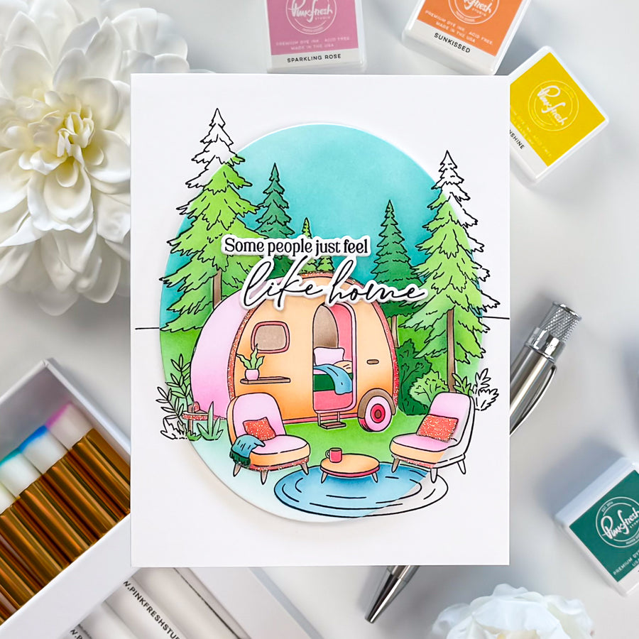Colorful illustration of a camper with trees and text on a white background, surrounded by craft supplies.