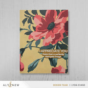 A rectangular art print or card featuring a large pink and red flower with dark green leaves on a warm beige background, with the text 'I APPRECIATE YOU more than a perfectly stamped image.' The piece is photographed against a light gray wood-textured backdrop.
