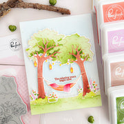 Card with tree and hammock design surrounded by Pinkfresh Studio products on a white surface