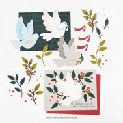 Handcrafted layered paper card set featuring three white doves with 'Peace', 'Joy', and 'Love' layered on top, surrounded by green and gold leafy branches with red berries. One card is dark green with repeating 'PEACE & JOY' text, another is light beige with 'Love to you all this holiday season', and all are layered over red and green backing cards, displayed on a clean white background with the brand Concord and 9th Design visible at the bottom.