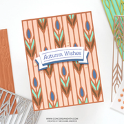 A handmade greeting card with a patterned autumn design, featuring vertical peach stripes, brown and teal leaf motifs, and a white banner reading 'Autumn Wishes'.