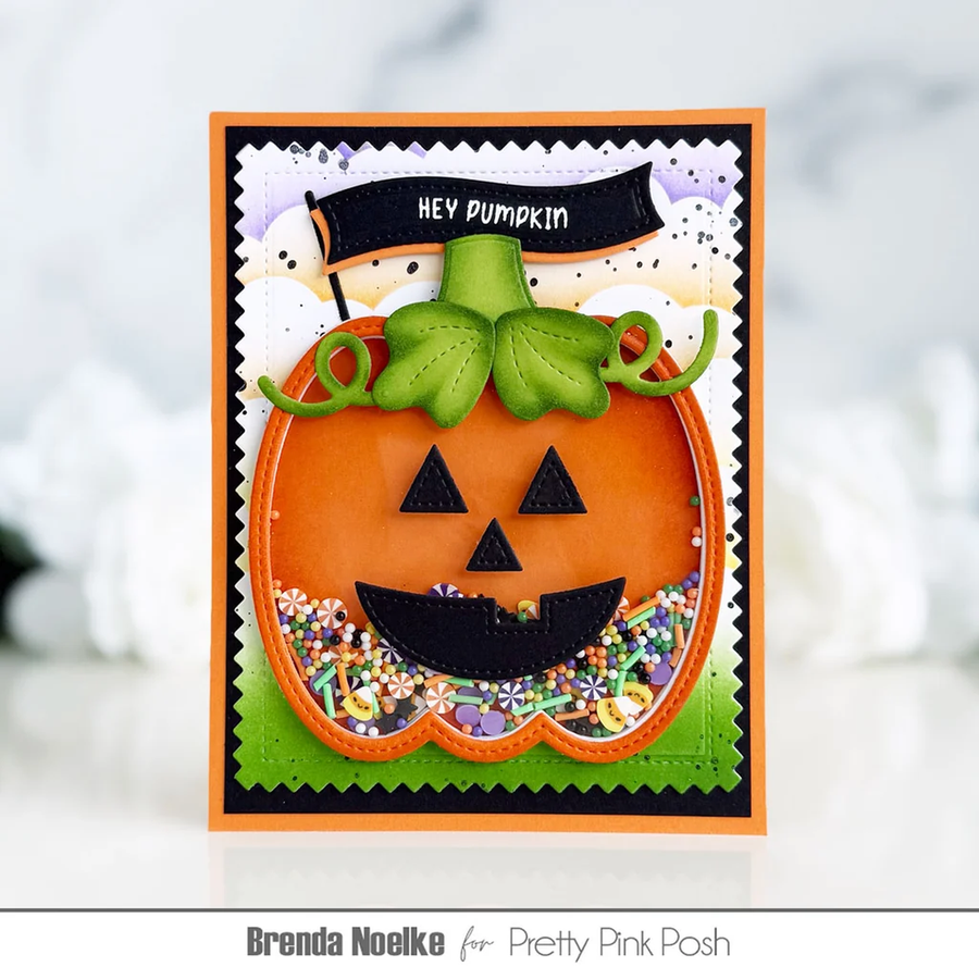 A handmade Halloween greeting card featuring a 3D layered jack-o'-lantern with a green stem, black facial features, and a colorful floral shaker underneath. The card has a black banner that reads 'HEY PUMPKIN' and is displayed on a light, blurred background.