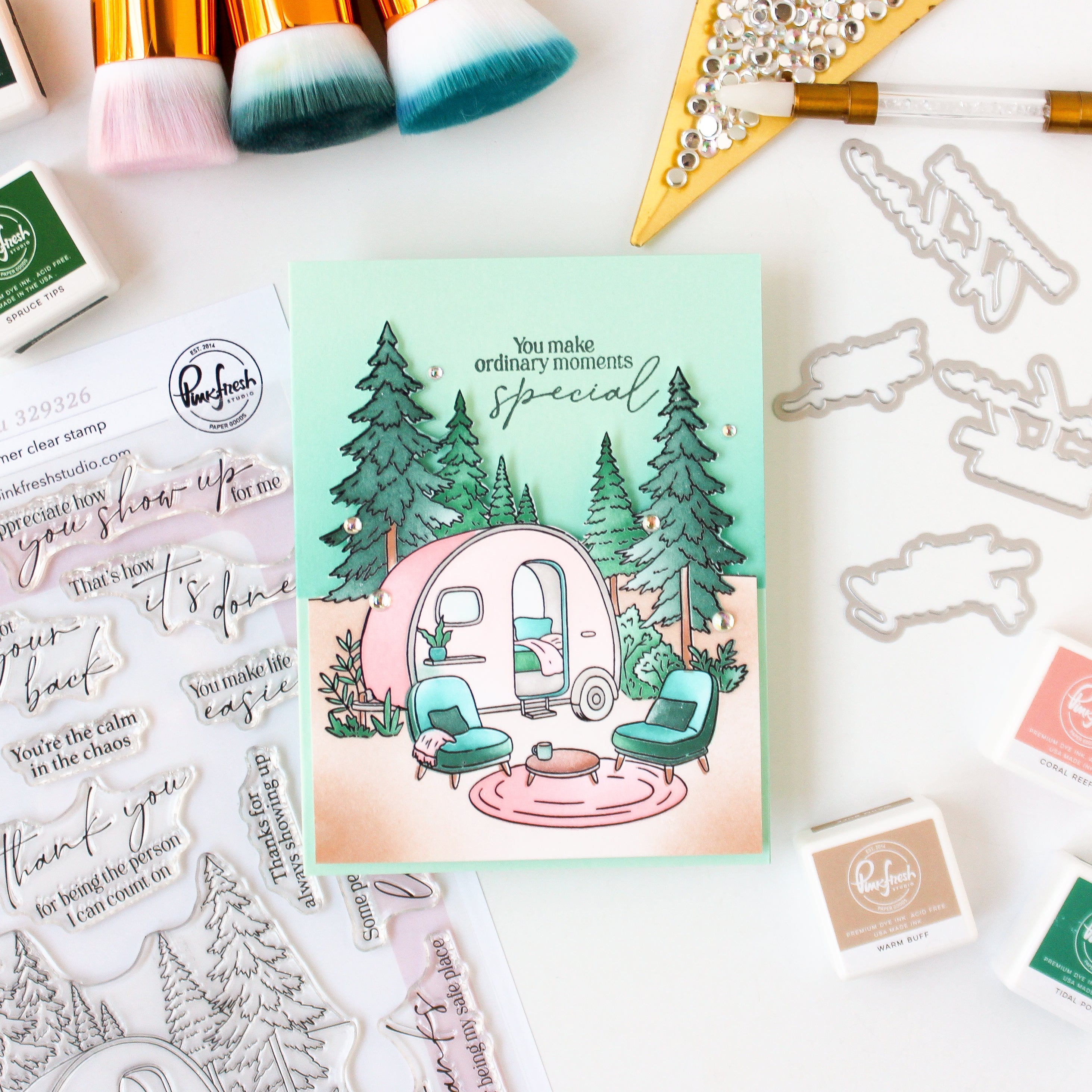 Card with a camper illustration surrounded by trees and decorative stamps on a white background