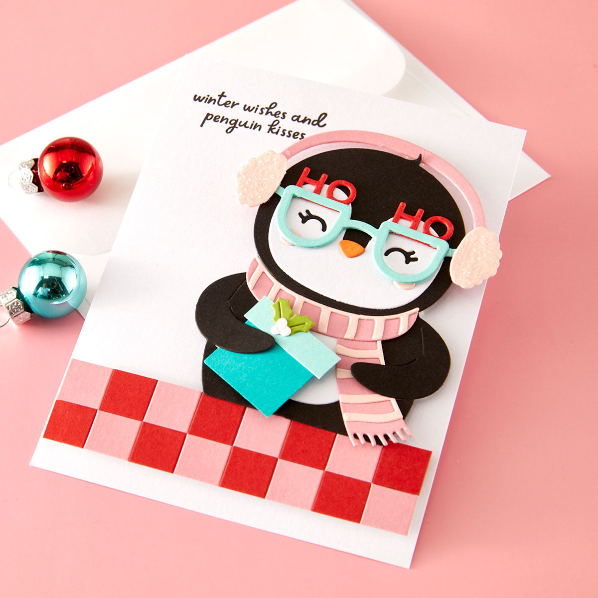 Card with a penguin wearing glasses and a scarf on a pink background Spellbinders Spectacular Christmas collection