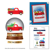 A collage showing a red pickup truck holiday craft design in multiple forms: a flat truck illustration, a snow globe version with a tree in the truck bed and the words 'DECK THE HALLS' and 'TIS THE SEASON,' plus a package sheet labeled 'Deck the Halls' with included die-cut elements. Spellbinders - Holiday Truck Scene Etched Dies by Simon Hurley