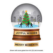 A festive snow globe illustration with a decorated Christmas tree, city skyline, and three silhouetted figures on a blue rink, set on a brown pedestal that reads 'JOYFUL WISHES.' Below the globe is a separate banner reading 'MERRY MOMENTS. Spellbinders City Skating Scene Etched Dies by Simon Hurley