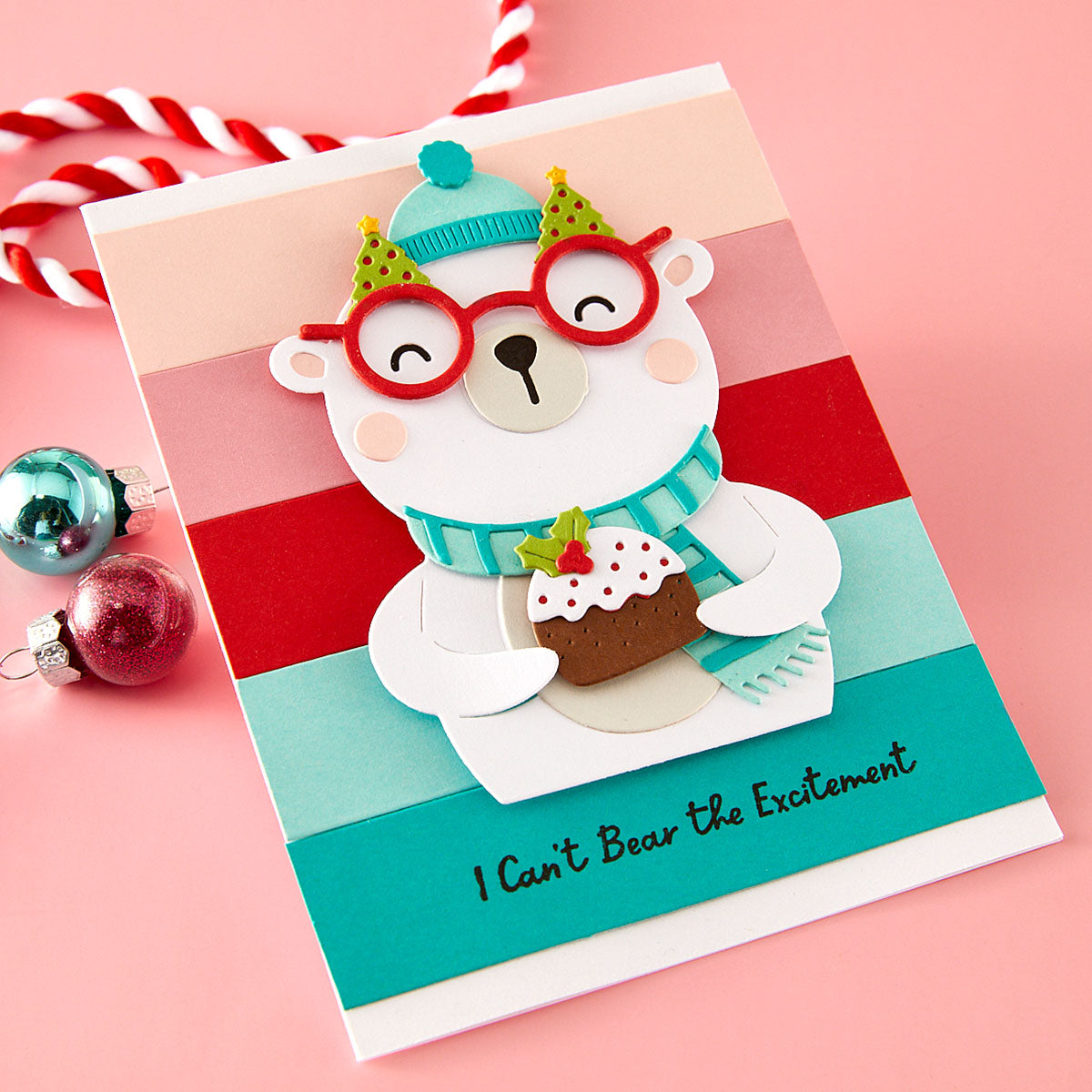 Christmas card with a polar bear holding a Christmas cake on a pink background using Spellbinders Spectacular Christmas collection