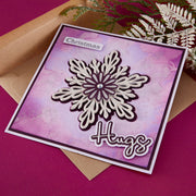 Greeting card with snowflake design and 'Christmas Hugs' text on a pink background using Spellbinders Layered Snowflakes Etched Dies by Lisa Horton