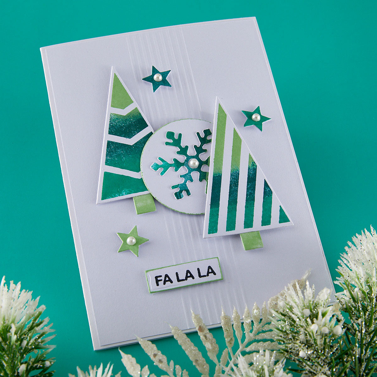 Christmas-themed card with trees, snowflake, and 'FA LA LA' text on a teal background.