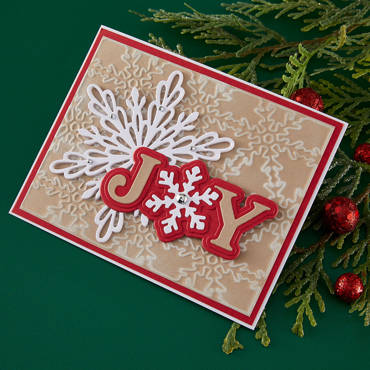 Christmas card with 'JOY' text and snowflake design on a green background