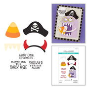 A craft stamp and embosser set featuring Halloween-themed designs: a candy corn, a black pirate hat with a skull and crossbones, a horned mask, a monster face, and text stamps reading 'Candy Coma Incoming,' 'Haunting the Snack Gable,' 'Snackula Strikes Again,' and 'Snackula Strikes Again Again.' The set includes a sample assembled card on a purple background and the retail package front on a white background. Spellbinders Snackula Stamp & Die Set