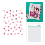 A sheet of die-cut paper snowflakes in pink and magenta tones displayed next to a card featuring a penguin and hot cocoa, and a package of Spellbindest Snowflakes die-cut paper. Spellbinders Snow Joy Stencil