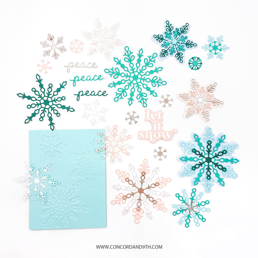 A flat lay of layered die-cut snowflakes and decorative paper elements in teal, aqua, blush pink, white, and metallic rose-gold tones, arranged on a white background with a light aqua embossed cardstock piece. No people or real environment are present.