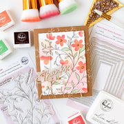 Floral card with 'Thanks' text surrounded by stamping supplies on a white background