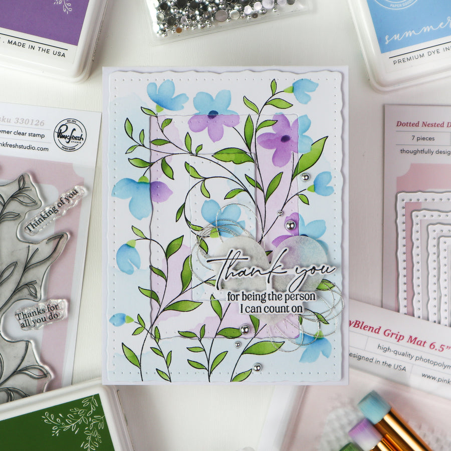Handmade card with floral design and 'thank you' message, surrounded by stamping supplies.