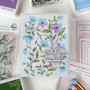 Handmade card with floral design and 'thank you' message, surrounded by stamping supplies.