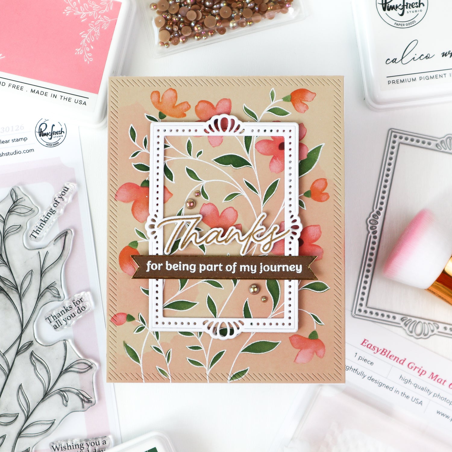 Floral card with 'Thanks for being part of my journey' text on a crafting surface with stamps and tools.