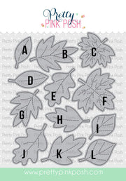 A sheet of letter-shaped leaf cutouts labeled A through L, shown on a branded Pretty Pink Posh cardstock template. The leaves are light gray with dashed center lines and black uppercase letters. Pretty Pink Posh Stitched Leaves Dies