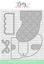 A craft die set by Pretty Pink Posh featuring a large quilted boot-shaped die, a smaller matching die, and a bow-shaped die, shown on a white background with the brand name and website. Pretty Pink Posh Stocking Gift Card Holder